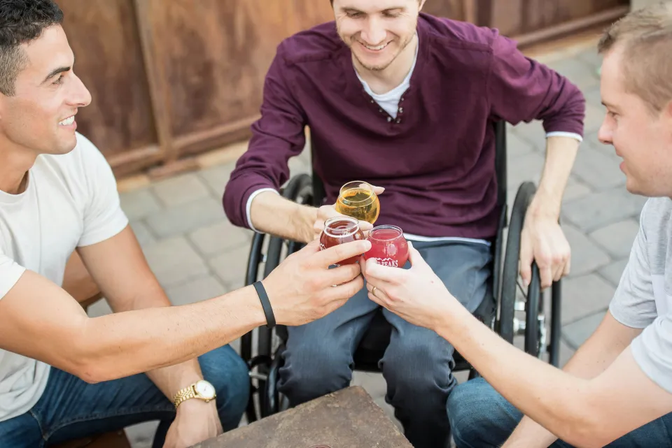 Man in a wheelchair sharing a drink with friends