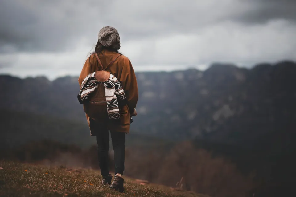 Solo traveler with a backpack facing the mountains
